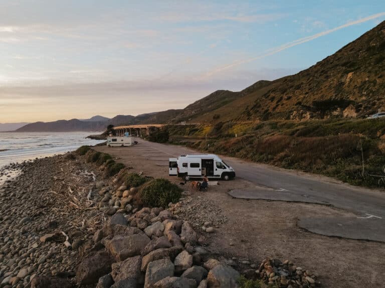 Van aménagé garé face aux montagnes au coucher du soleil